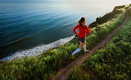 Young woman running beside sea